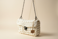Front three-quarter view of an ivory-white woven flap handbag with a chain strap