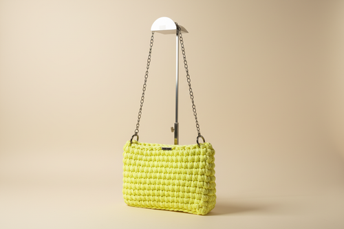 Front three-quarter view of a bright lemon-yellow woven shoulder bag with a chain strap