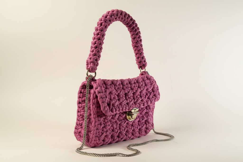 Front-left three-quarter view of a mauve woven shoulder bag with a chain strap and gold-tone clasp