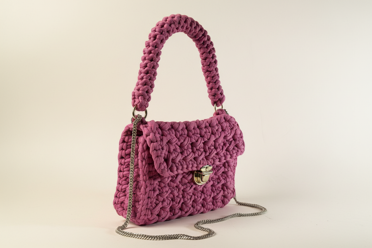 Front-left three-quarter view of a mauve woven shoulder bag with a chain strap and gold-tone clasp