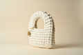 Front three-quarter view of an ivory-white handwoven handbag with a rounded top handle