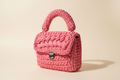 Three-quarter view of a bright rose-pink woven handbag with a rounded handle and silver-tone clasp