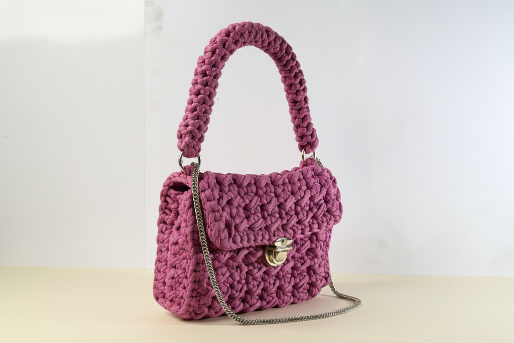 Front-right three-quarter view of a mauve woven shoulder bag with a chain strap and gold-tone clasp