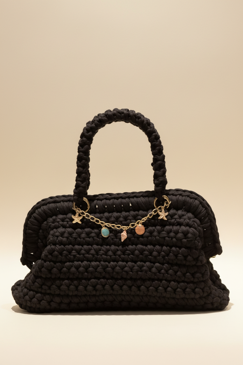 Full-frame front view of the black crochet charm-chain handbag